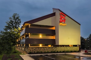 A Red Roof Plus hotel with a two-story structure, a stone facade, and a parking lot.