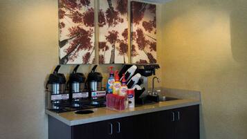 Una kitchenette equipada con cafetera, hervidoras y un lavamanos.