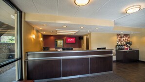 A reception desk with a flat-screen TV displaying 'Free Wi-Fi All Rooms' in a hotel lobby.