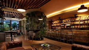 Una zona de bar con techo de madera, luces colgantes y una variedad de botellas en estantes.