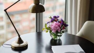 Un bureau avec une lampe, un vase de fleurs et un livre.