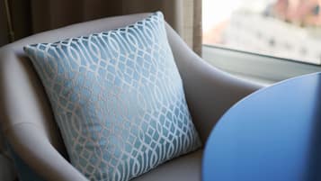 A chair with a patterned cushion and a window with a view of buildings.