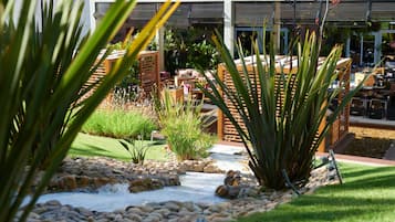 A garden pathway with rocks and plants, outdoor seating, and a building with a covered patio area.