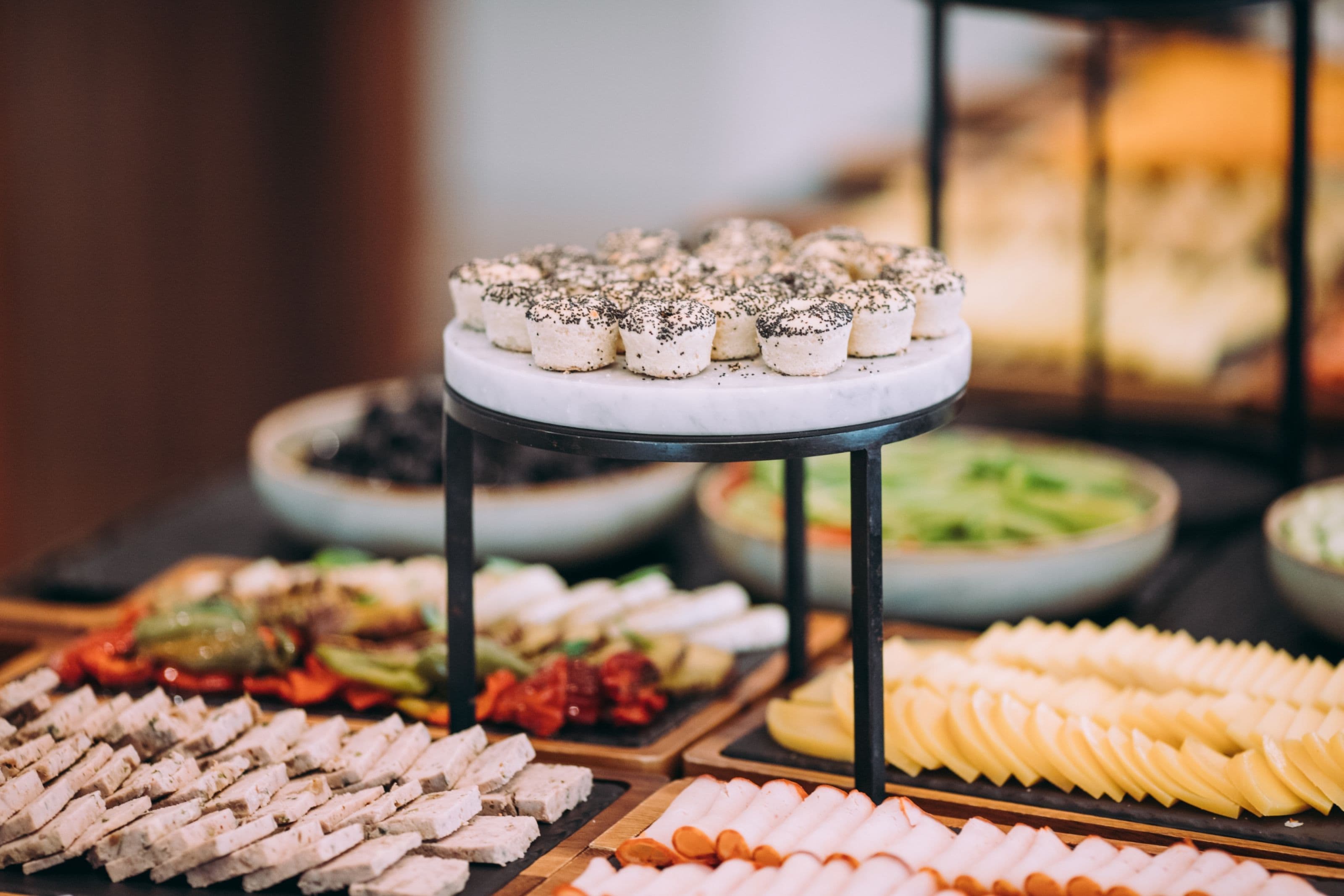 Un buffet proposant une variété de plats, notamment des viandes et des fromages en tranches, ainsi que des légumes.