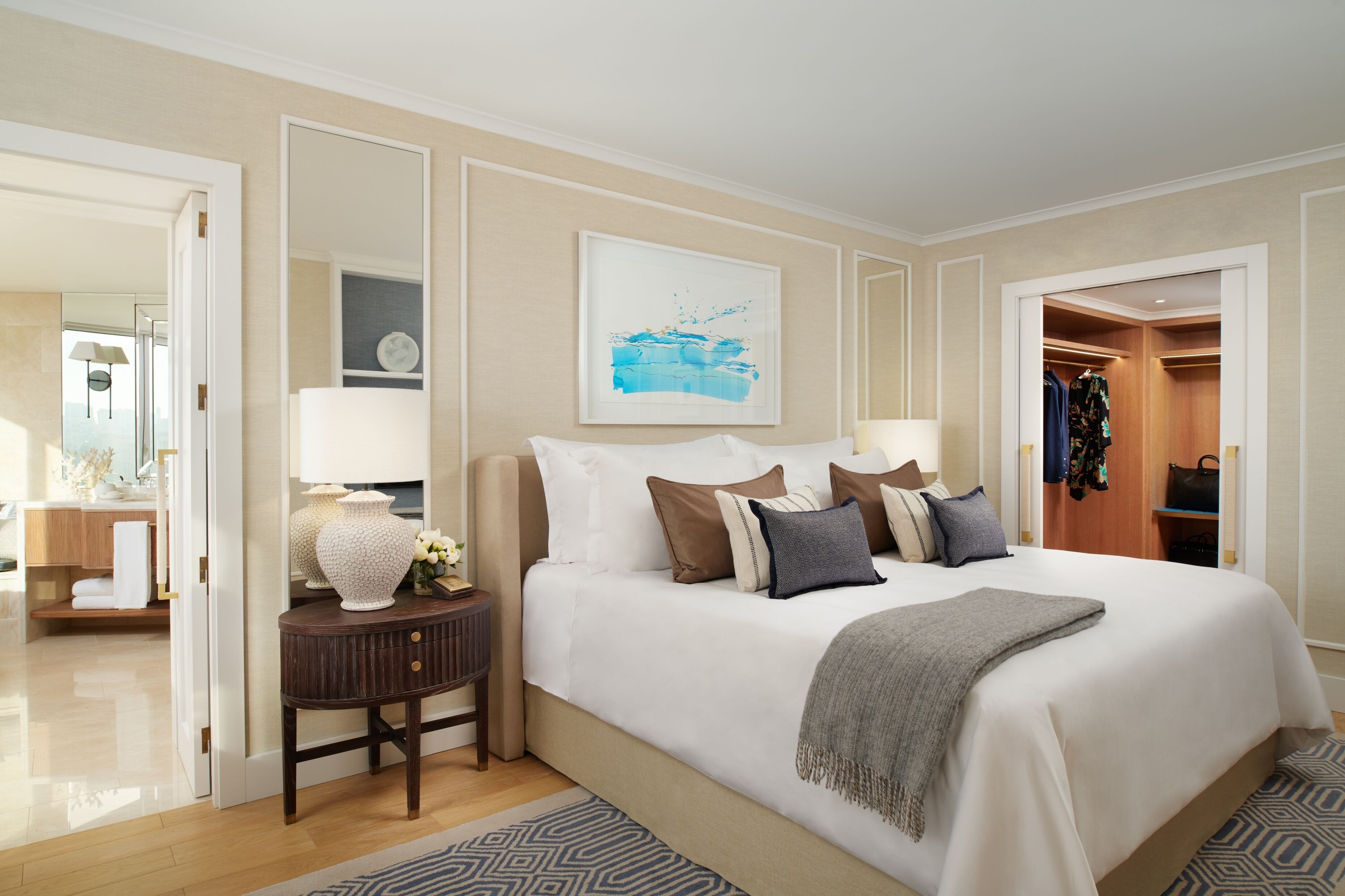 A spacious bedroom with a large bed, bedside tables, a mirror, and a wardrobe.