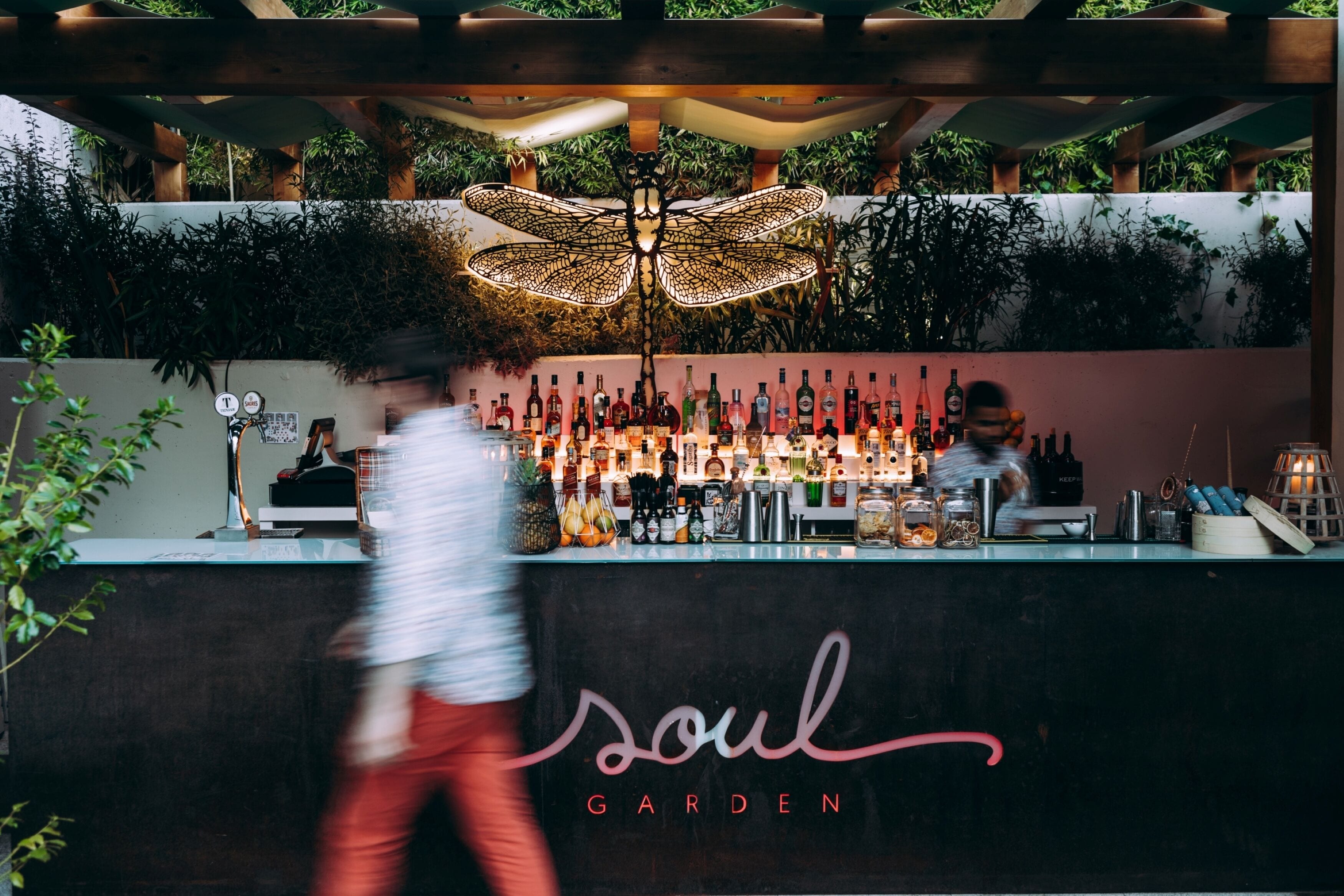 Zona de bar con una variedad de botellas y un cartel que dice "soul garden".