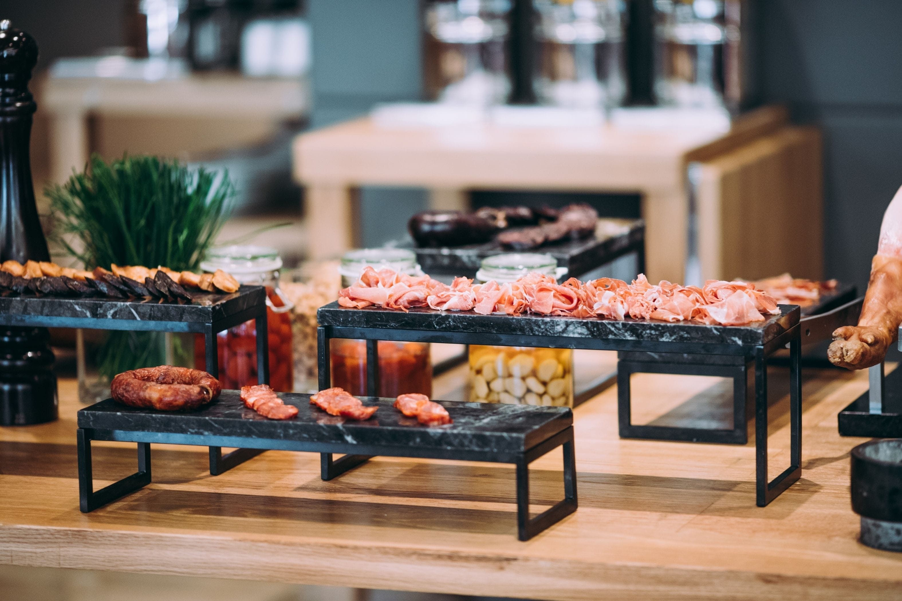 A buffet table with various meats and cheeses.