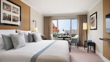A hotel room with a large bed, a desk, a chair, and a TV.
