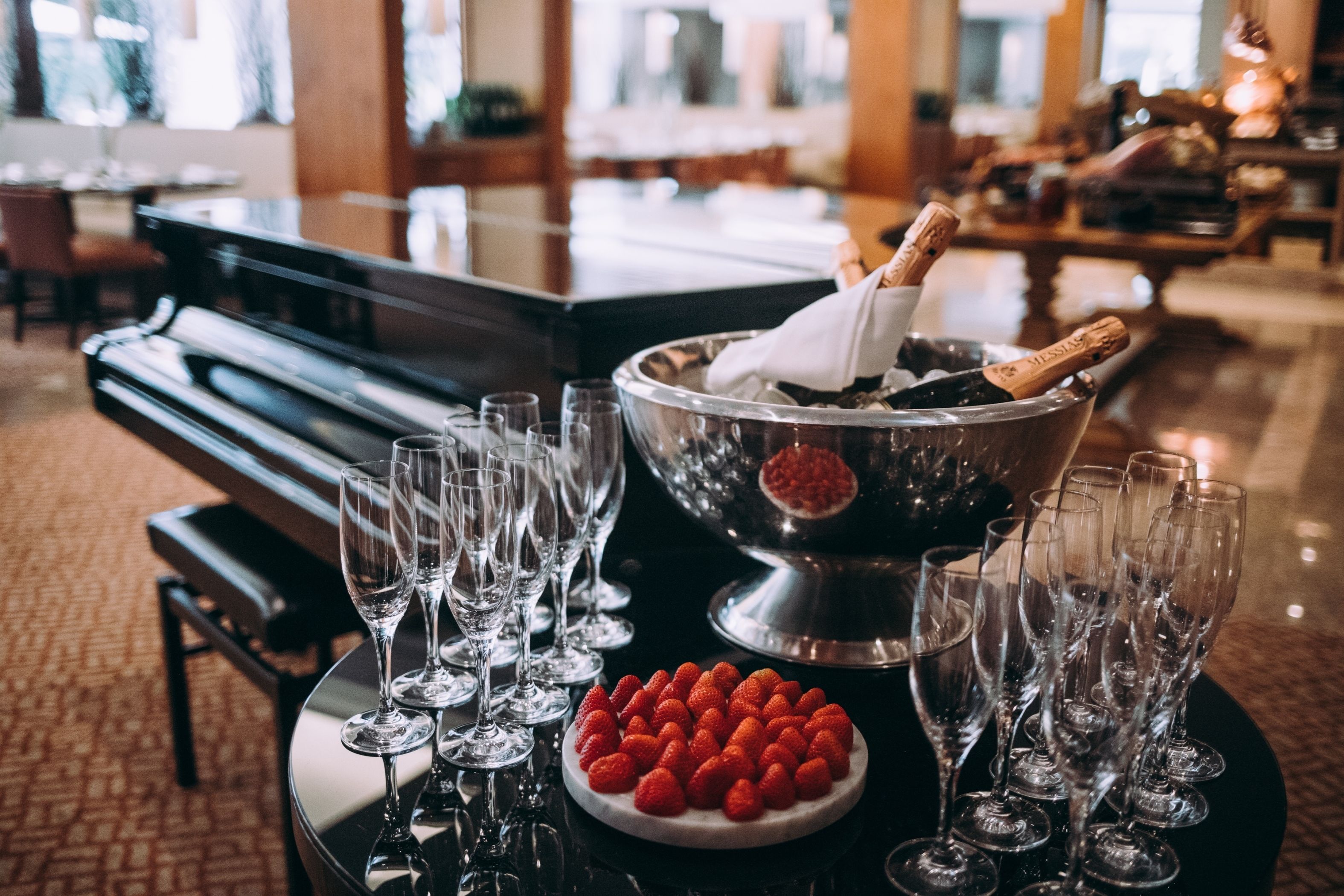 A table with champagne glasses, a bowl of strawberries, and a bottle of champagne in a bucket.