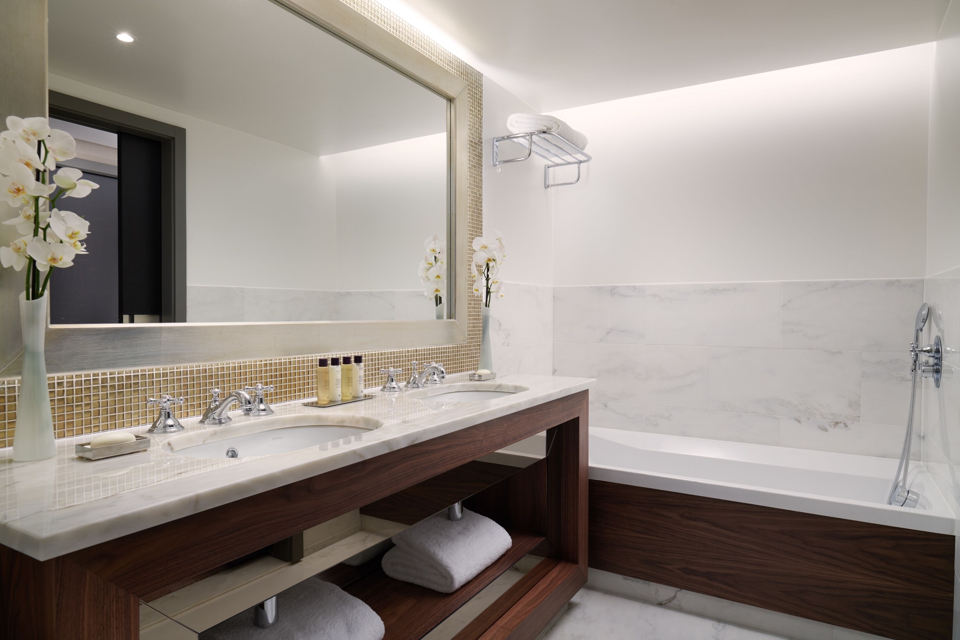 Un baño moderno con dos lavamanos, un espejo grande y una bañera.