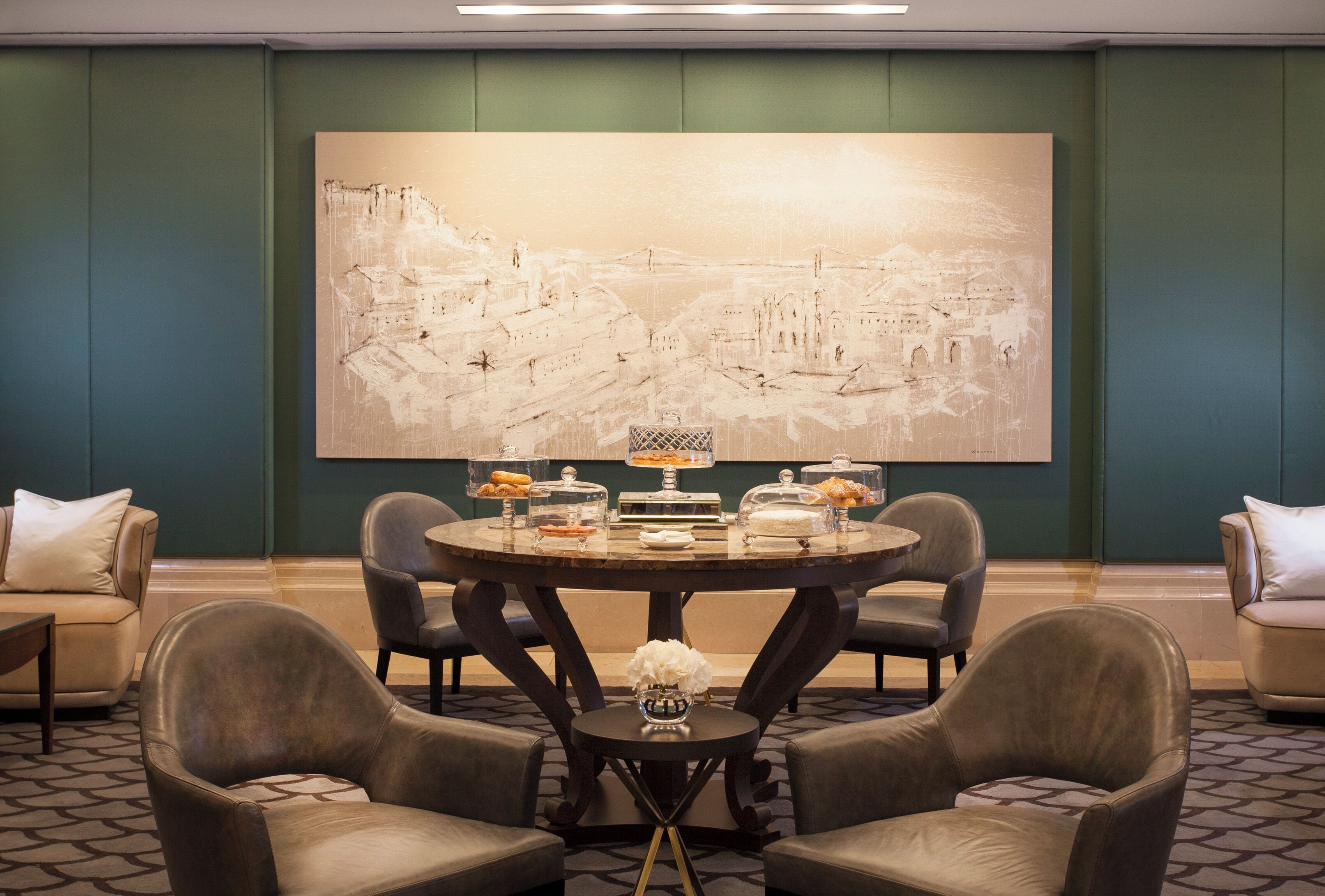 Un espace repas comprenant une table ronde, des chaises et un grand tableau abstrait accroché au mur.