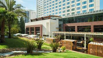 Experience the hotel's sleek, contemporary design, featuring a spacious outdoor area with lush greenery and comfortable seating.