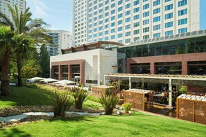 A modern hotel with a rooftop bar, outdoor seating, and a well-maintained garden.