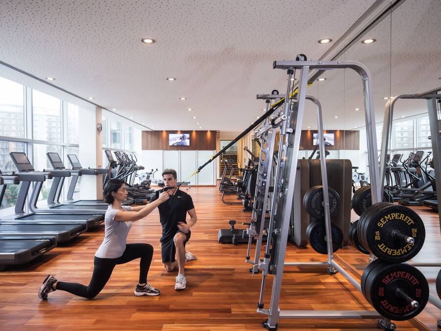 Et fitnesscenter med løbebånd, styrkemaskiner og et spejl.