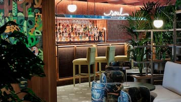 A bar area with a wooden wall, bar stools, and a neon sign.