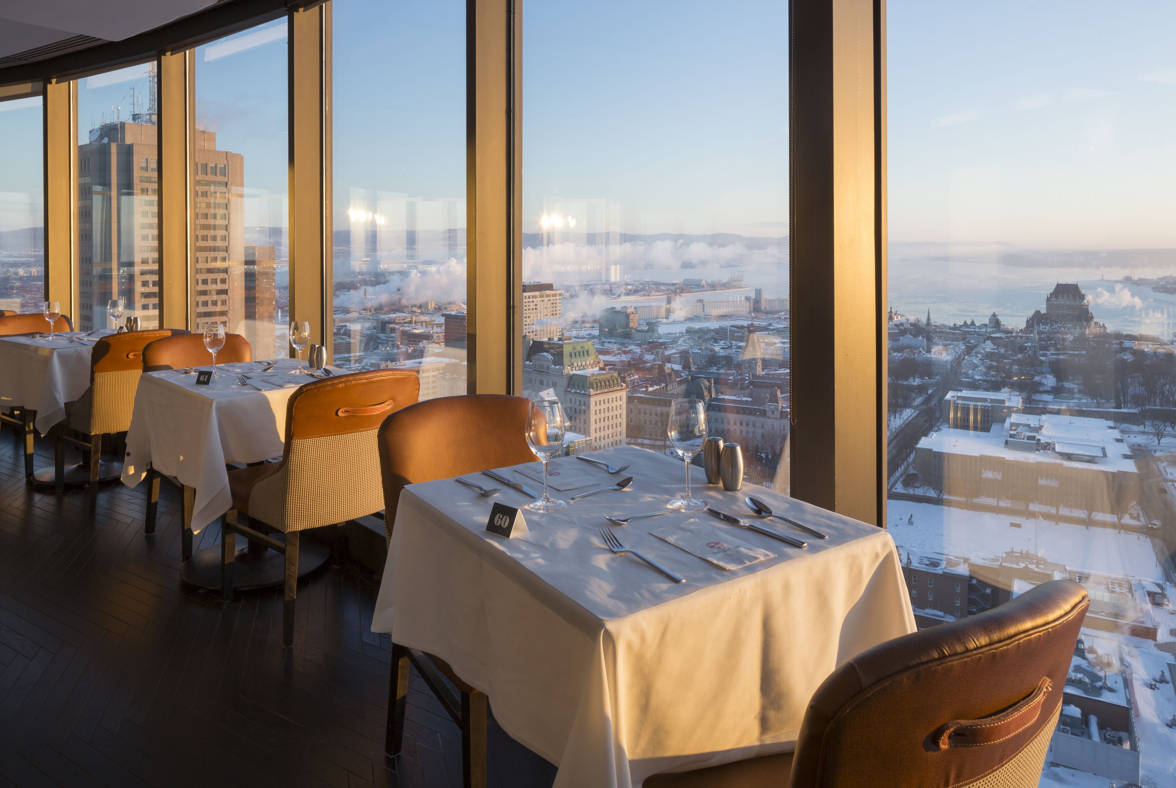 A restaurant with tables set for dining, large windows offering a city view.