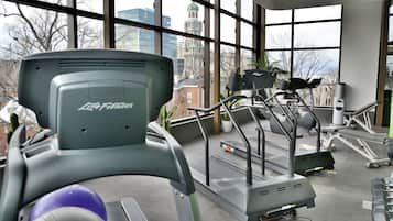 Une salle de sport équipée de tapis de course, d’haltères et de ballons d’exercice.