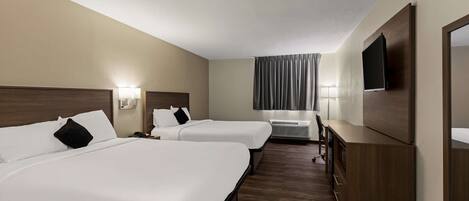 A hotel room with two beds, a TV, a desk, and a window with curtains.