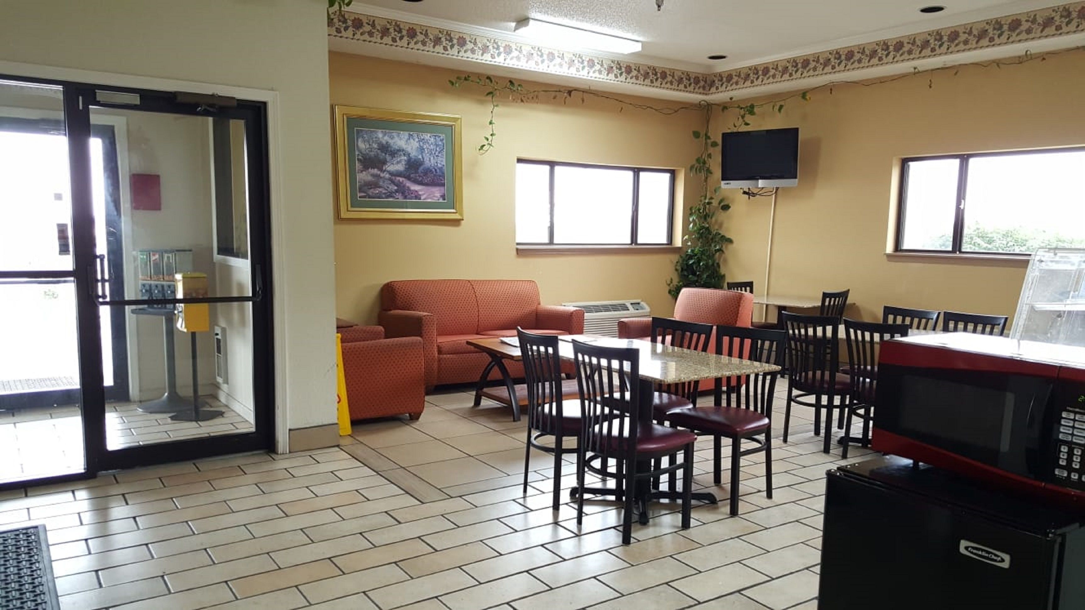 A dining area with a table and chairs, a sofa, a television, and a microwave.