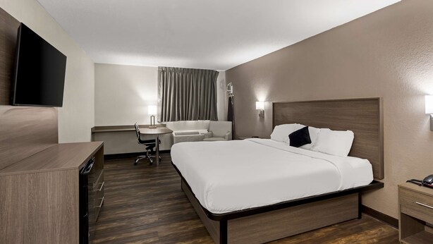 Een hotelkamer met een bed, nachtkastje, bureau, stoel en een flatscreen-televisie.