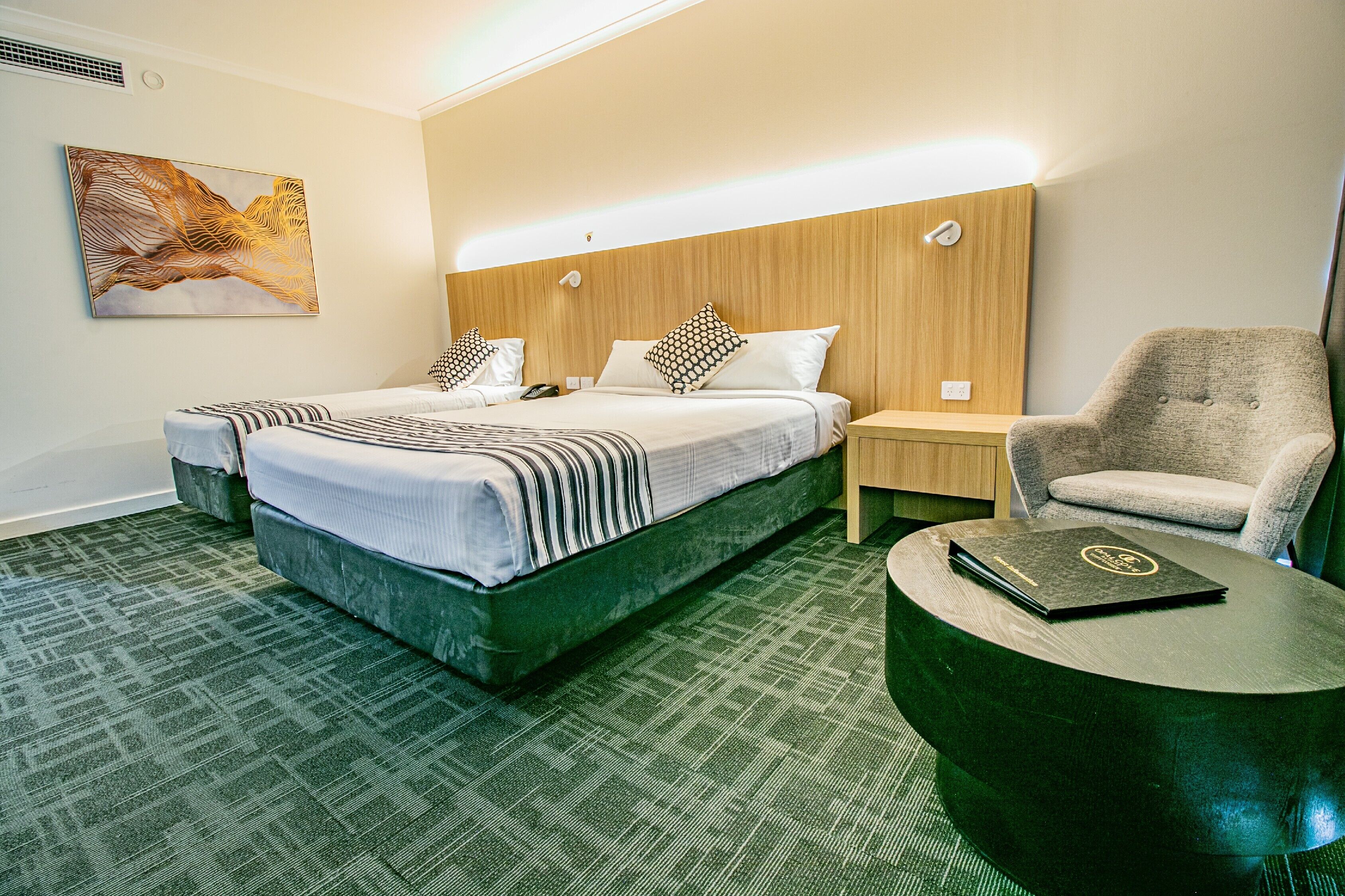 A hotel room with a large bed, two bedside tables, a chair, a desk, and a painting on the wall.