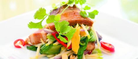 A dish with a variety of vegetables and a piece of meat on a white plate.