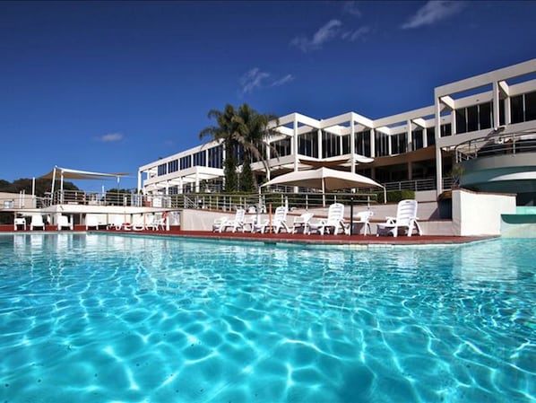 Una piscina al aire libre, sombrillas