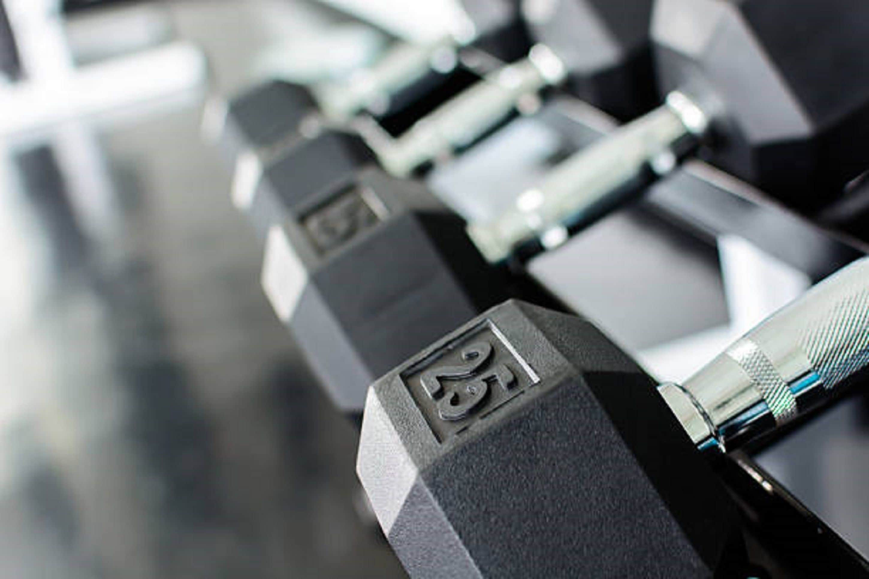 A close-up of a row of black dumbbells with weight markings.