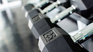 A close-up of a row of black dumbbells with weight markings.