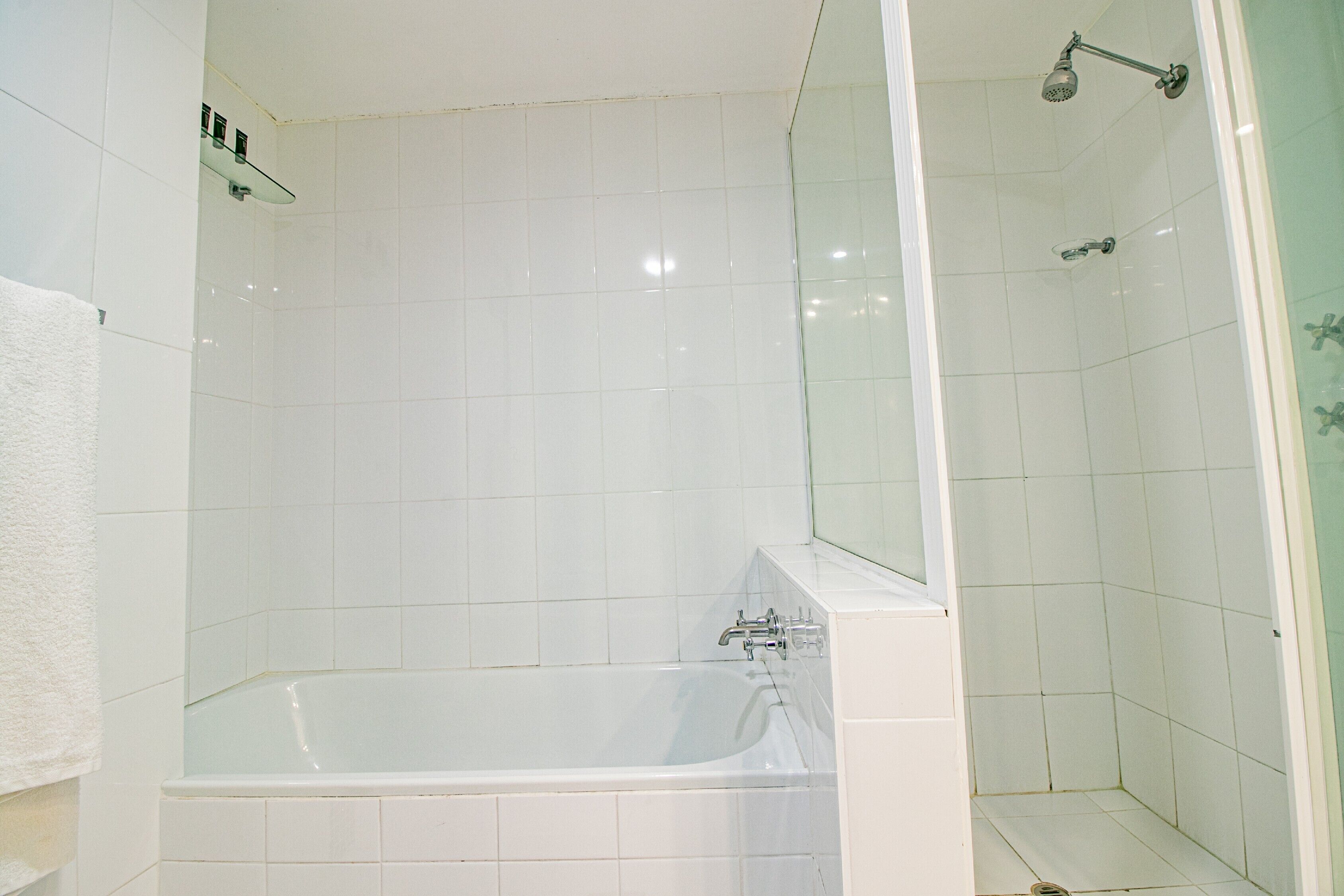 Un baño con bañera, ducha y zona de ducha con mampara de vidrio.