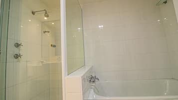 Une salle de bain moderne dotée d’une douche à parois de verre, d’une baignoire séparée et d’un grand miroir.
