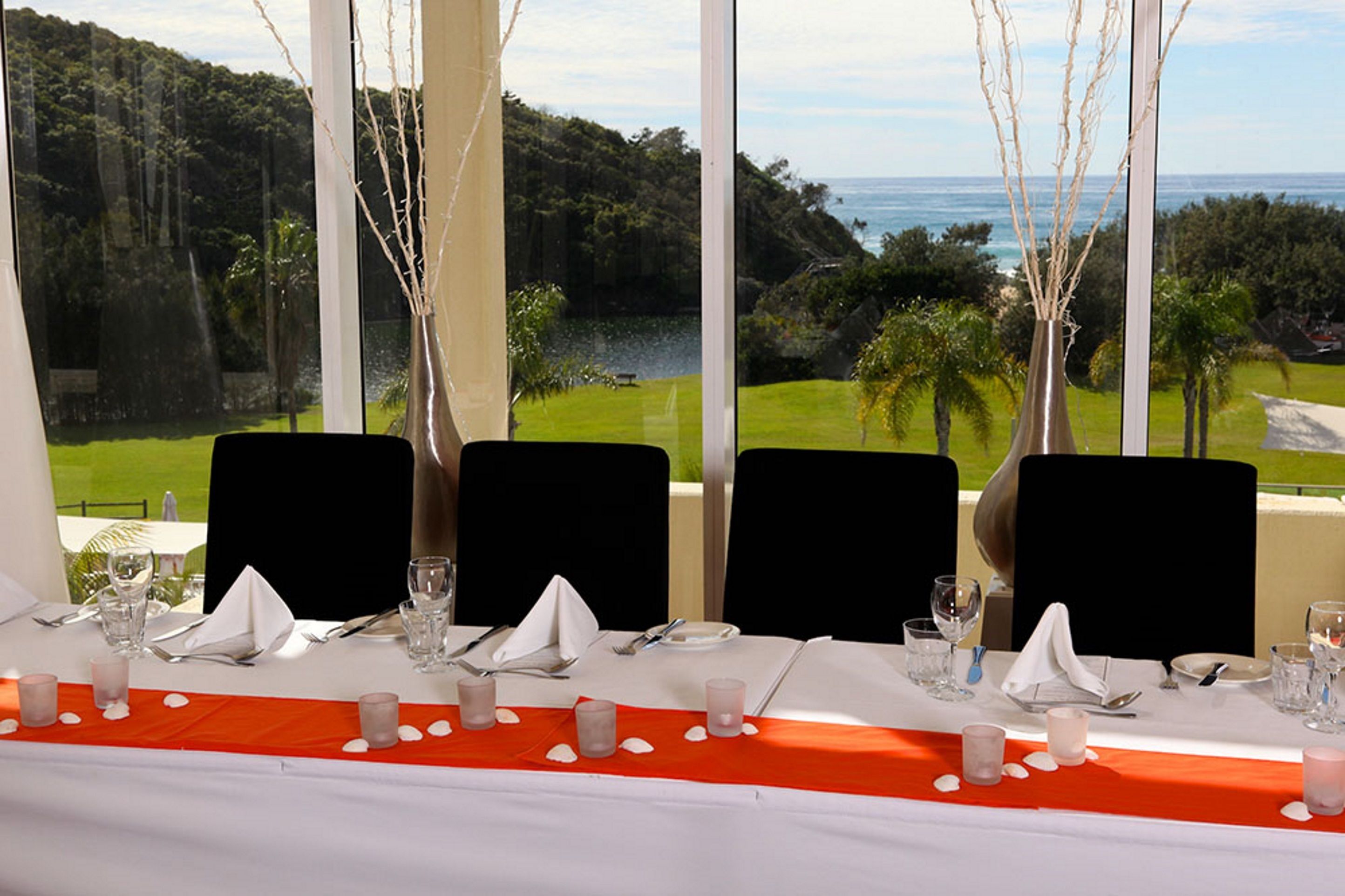 A table set for four with a view of a golf course and ocean.