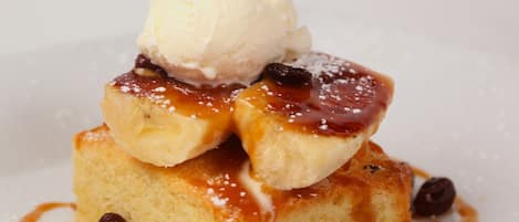 Un postre con una bola de helado, salsa de caramelo y pasas.