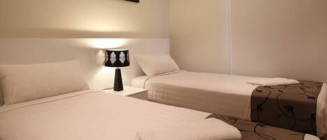 A hotel room with two beds, a nightstand with a lamp, and a wall-mounted artwork.