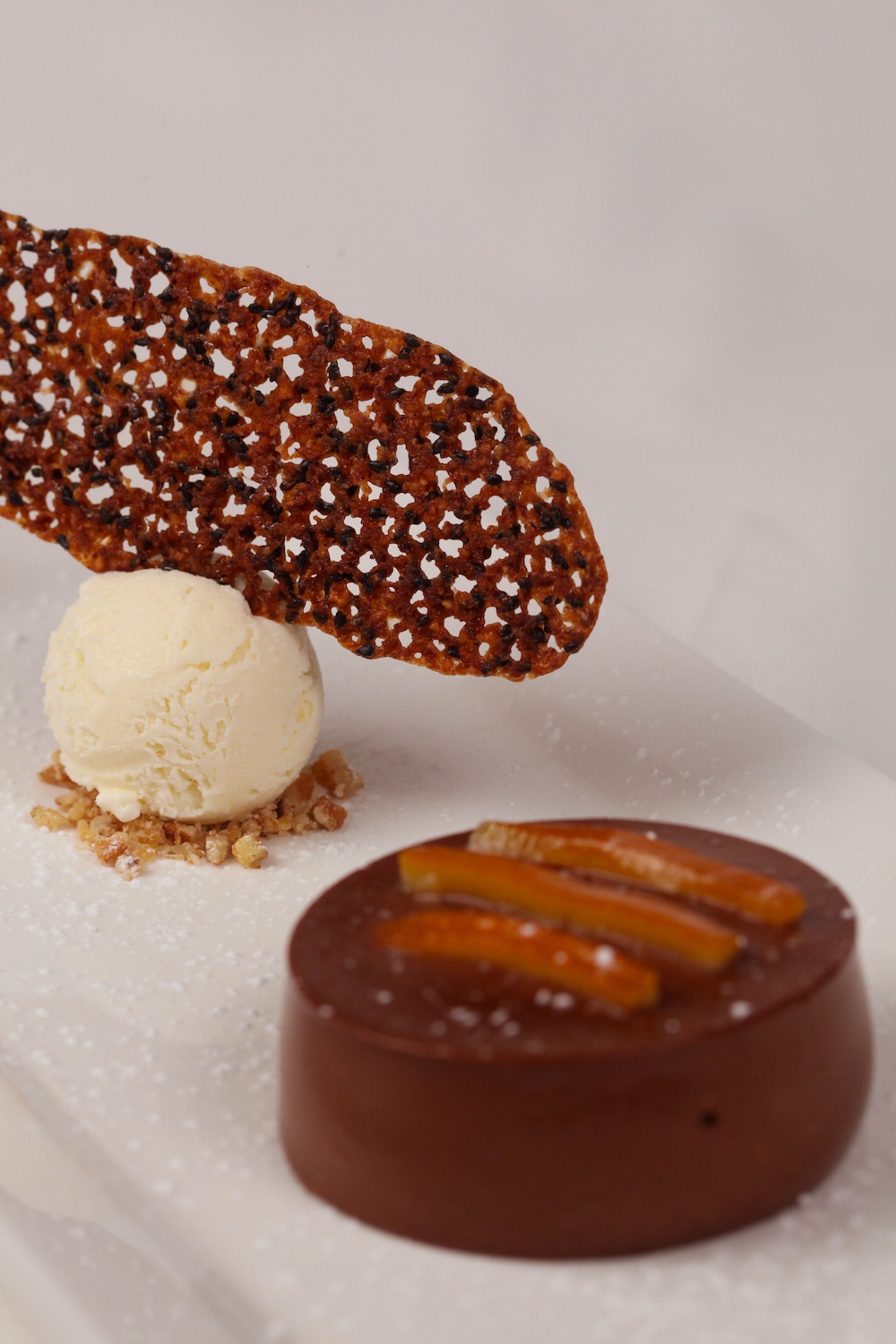 A dessert with a scoop of ice cream, a chocolate-covered item, and caramel sticks.