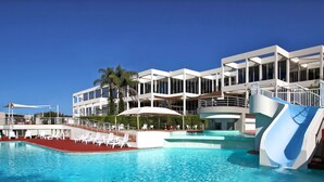 A modern hotel with a pool area, including a water slide and lounge chairs. - Opal Cove Resort (Korora)