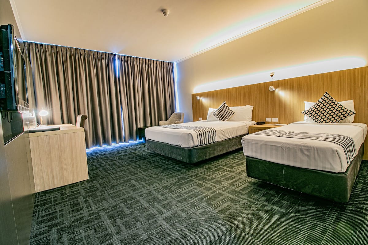 A hotel room with two beds, a desk, and a TV.