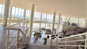 A spacious indoor area with a high ceiling, large windows, and multiple levels connected by staircases. - Opal Cove Resort (Korora)
