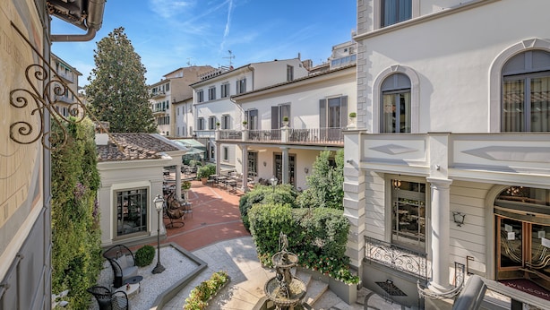 A courtyard with a fountain, outdoor seating, and a view of surrounding buildings.
