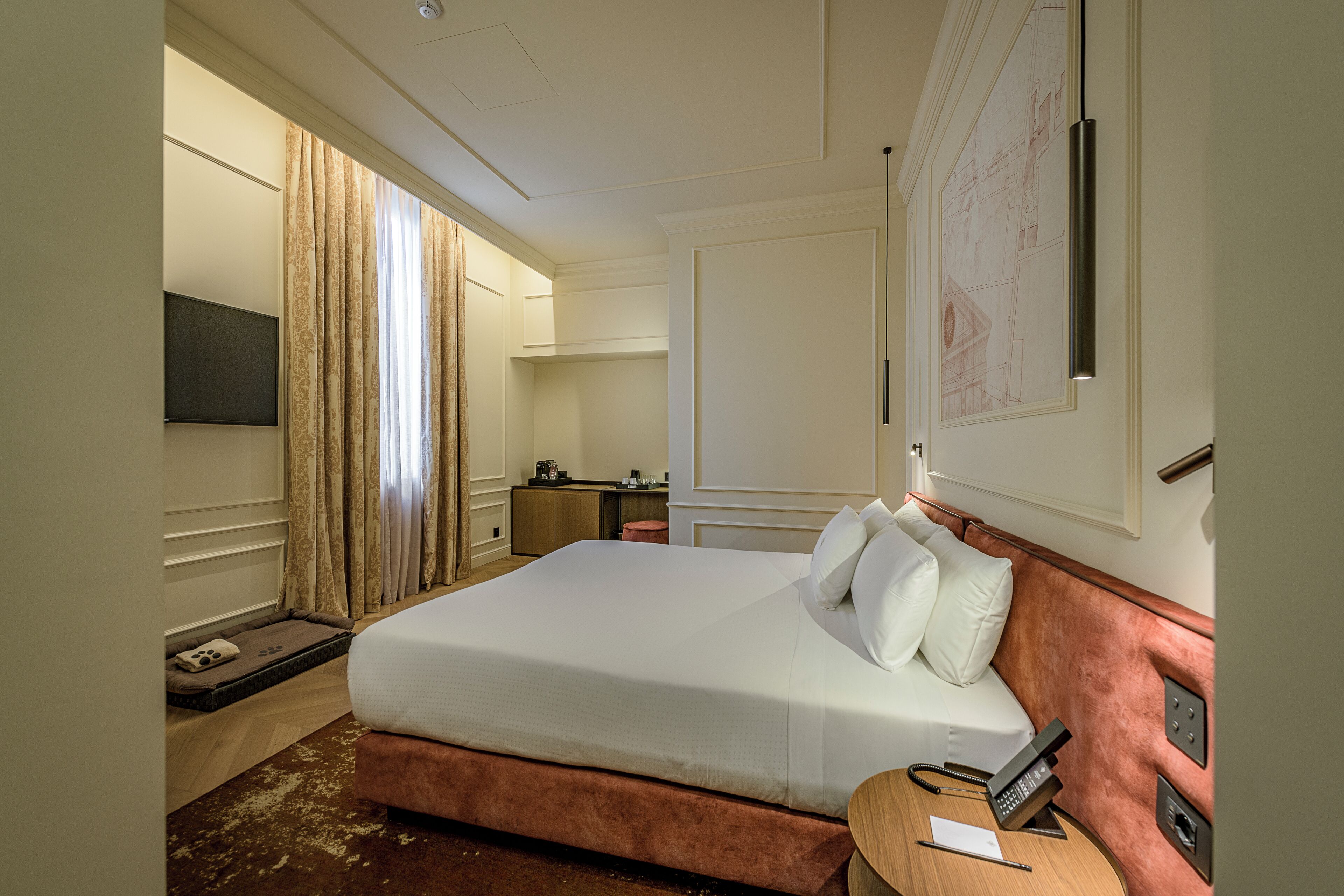 Habitación de hotel con una cama grande, un escritorio con teléfono, una pequeña zona de estar y televisión.