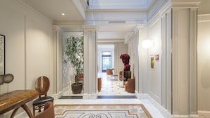 A spacious hallway with a patterned floor, a potted plant, and a red sculpture.