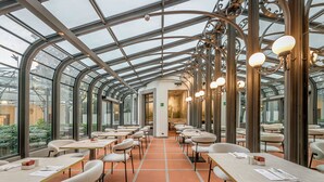 A restaurant with a glass ceiling, white chairs, and tables.