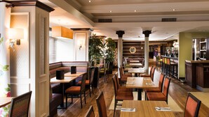 Een restaurant met zitbankjes, tafels en een bar.