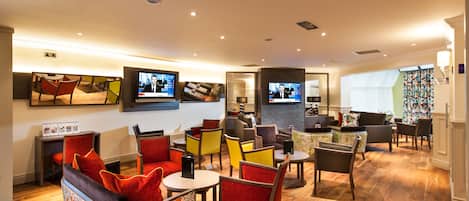 A modern lounge area with comfortable seating, a flat-screen TV, and a well-lit space.