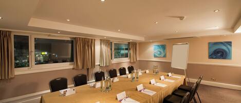 A conference room with a long table, chairs, and a whiteboard.