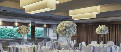 A banquet hall with round tables, white tablecloths, and chairs with white sashes.