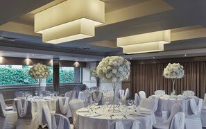 A banquet hall with round tables, white tablecloths, and chairs with white sashes. - Leonardo Inn Glasgow West End (Glasgow)