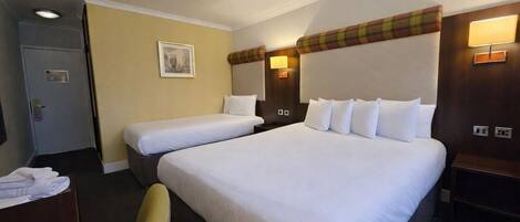 Une chambre d’hôtel avec deux lits, un bureau, une chaise et une porte.