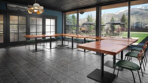 A modern dining area with large windows, geometric patterned flooring, and a view of mountains.