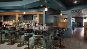 A bar area with multiple stools, a bar counter, and a variety of bottles.